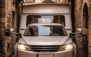 Auto mit Wohnwagen in enger Gasse