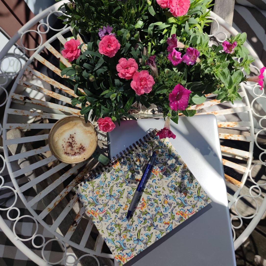 Startseite 13 Laptop, Notizbuch, Cappuchino und Blumen auf Gartentisch